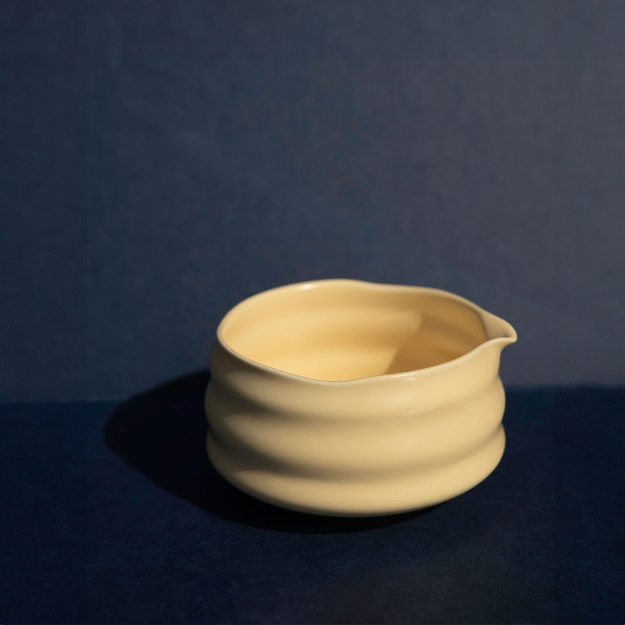 Yellow-colored ceramic bowl on a dark blue background